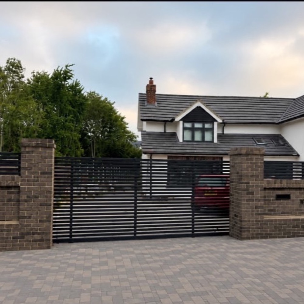 Block-paved driveway with slatted gates and brick boundary wall